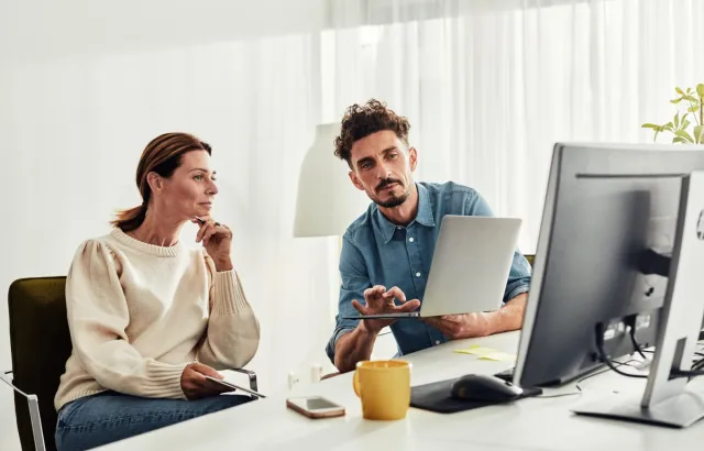 Person showing woman how to use customer portal on laptop