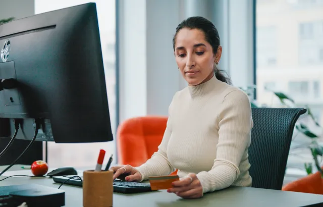 Woman working at her desk, while looking at her Circle K Pro card